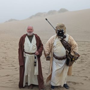 Two people dressed in Star Wars costumes pose in the sand dunes