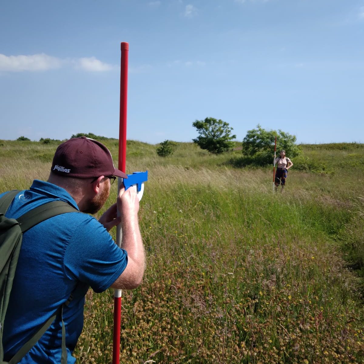 A man stands in the dunes using measuring equipment
